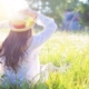 Women laying in field of flowers holding her sun hat free of allergies