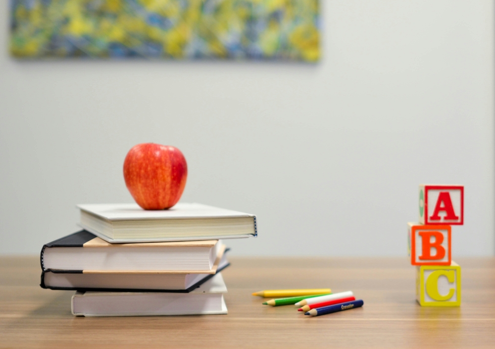 School supplies of apple, books, pencils and blocks sitting on desk