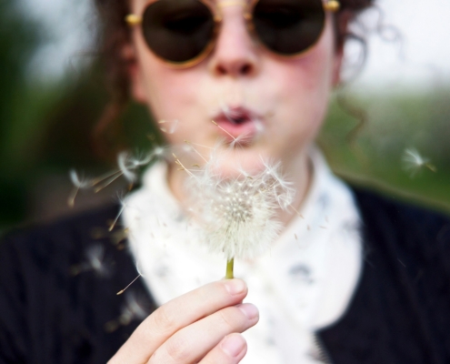 Woman blowing a dandelion.