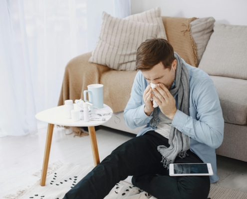 Man sneezing next to his over-the-counter allergy medications