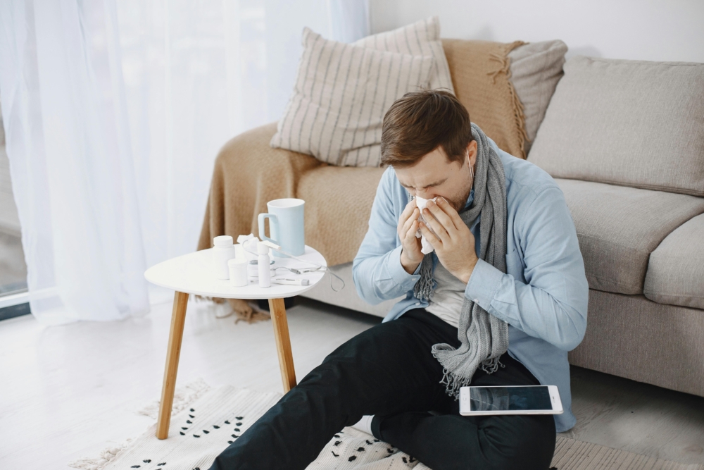 Man sneezing next to his over-the-counter allergy medications