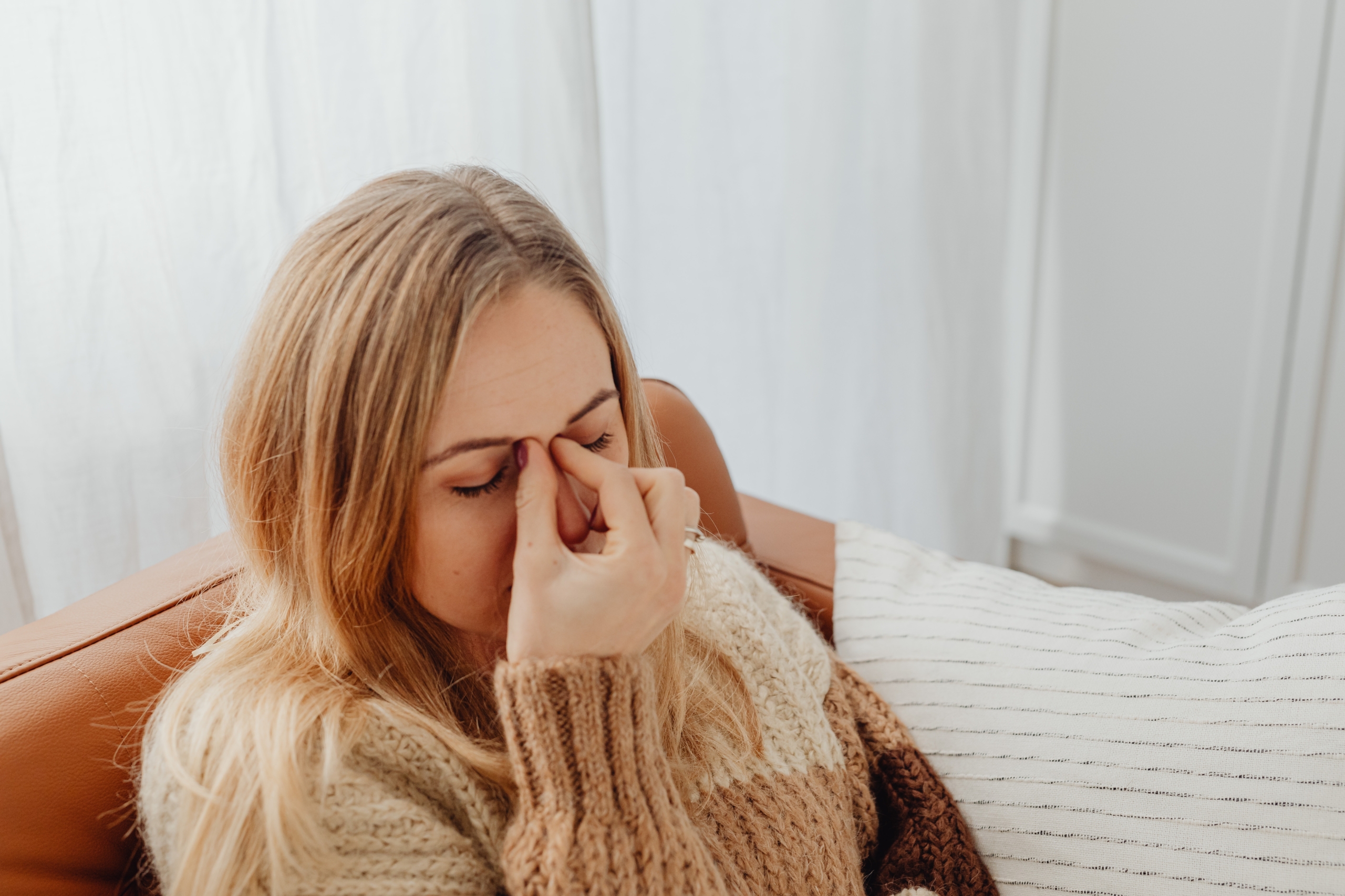 Woman dealing with sinus pressure caused by indoor allergies during winter